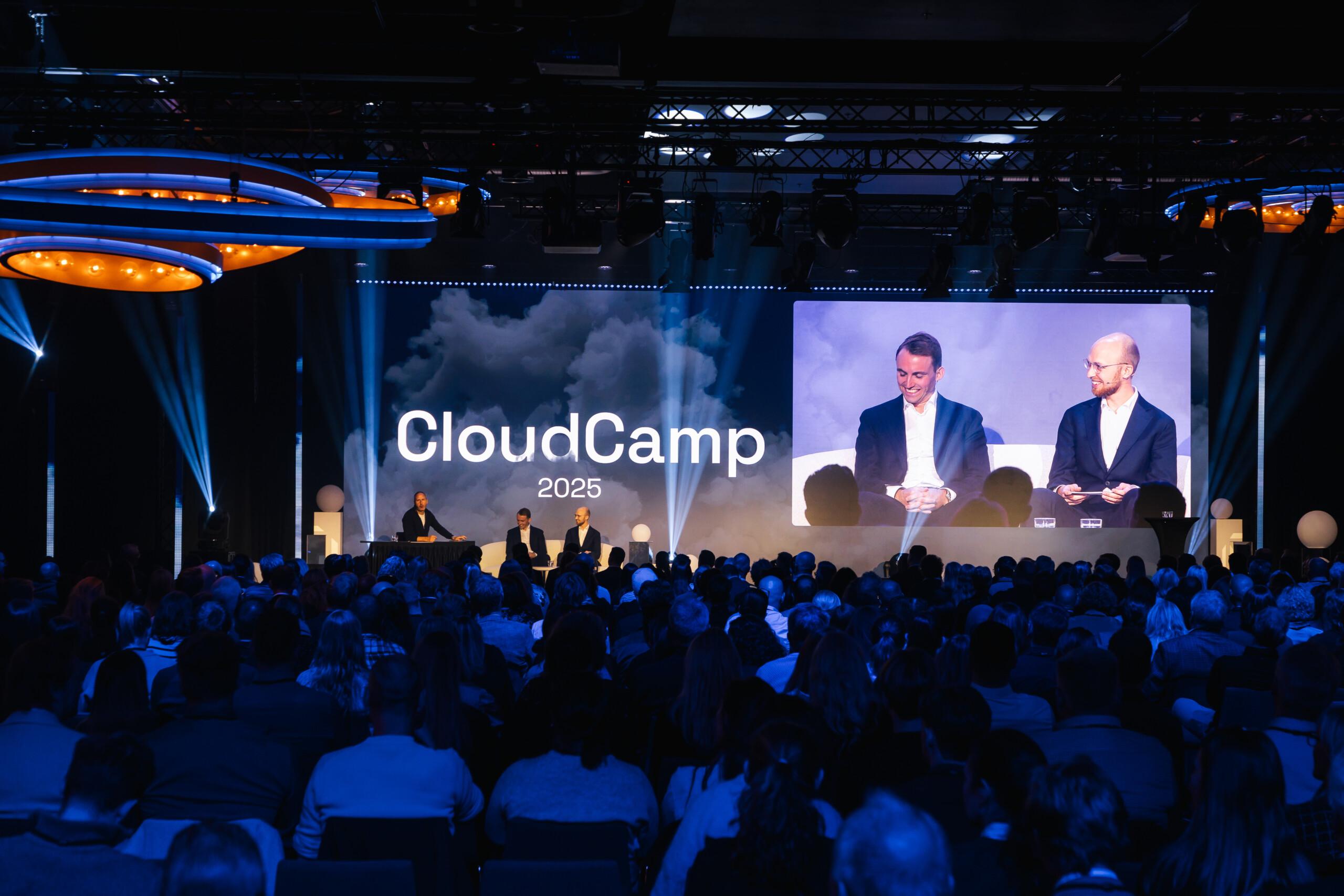 CloudCamp 2025 event shows the stage and people.