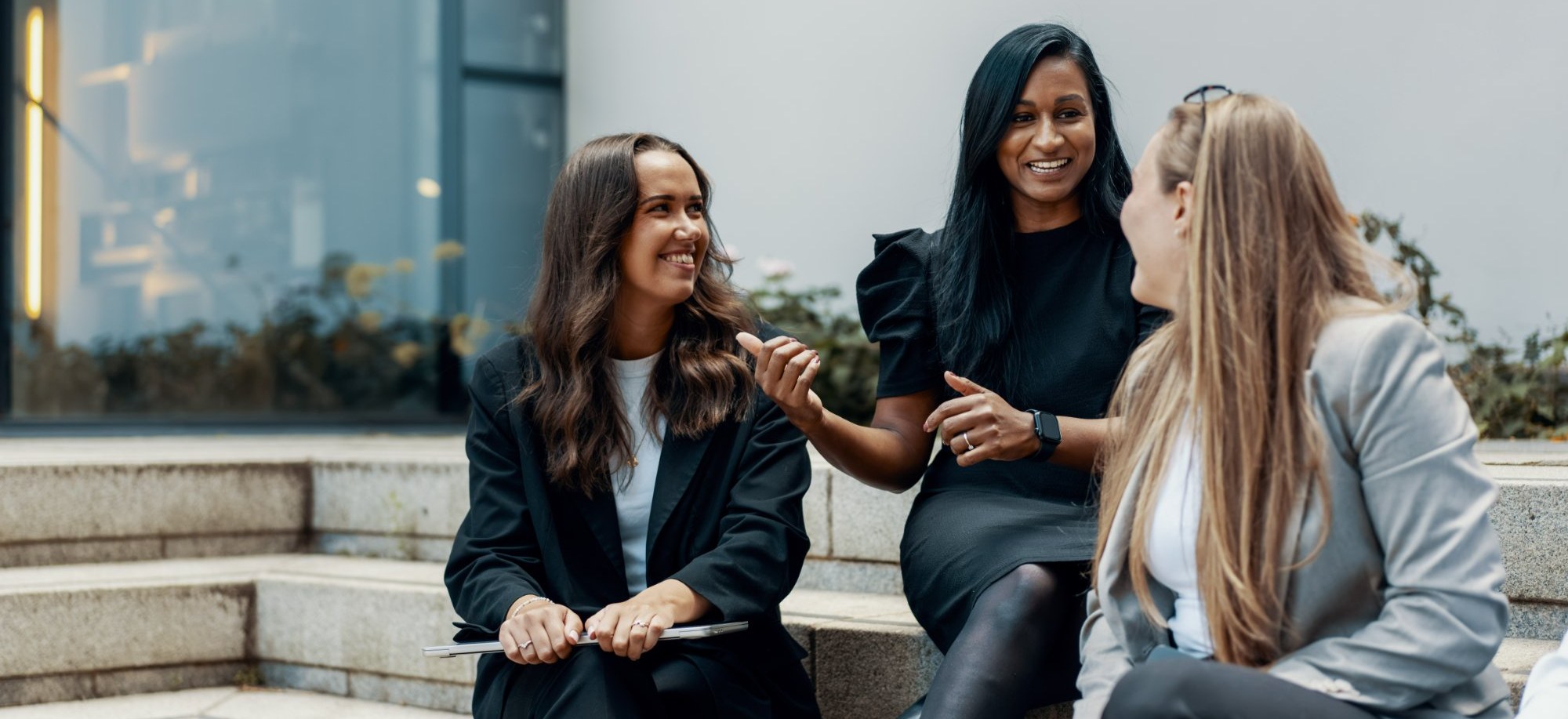 Three colleagues chatting and smiling on the office steps
